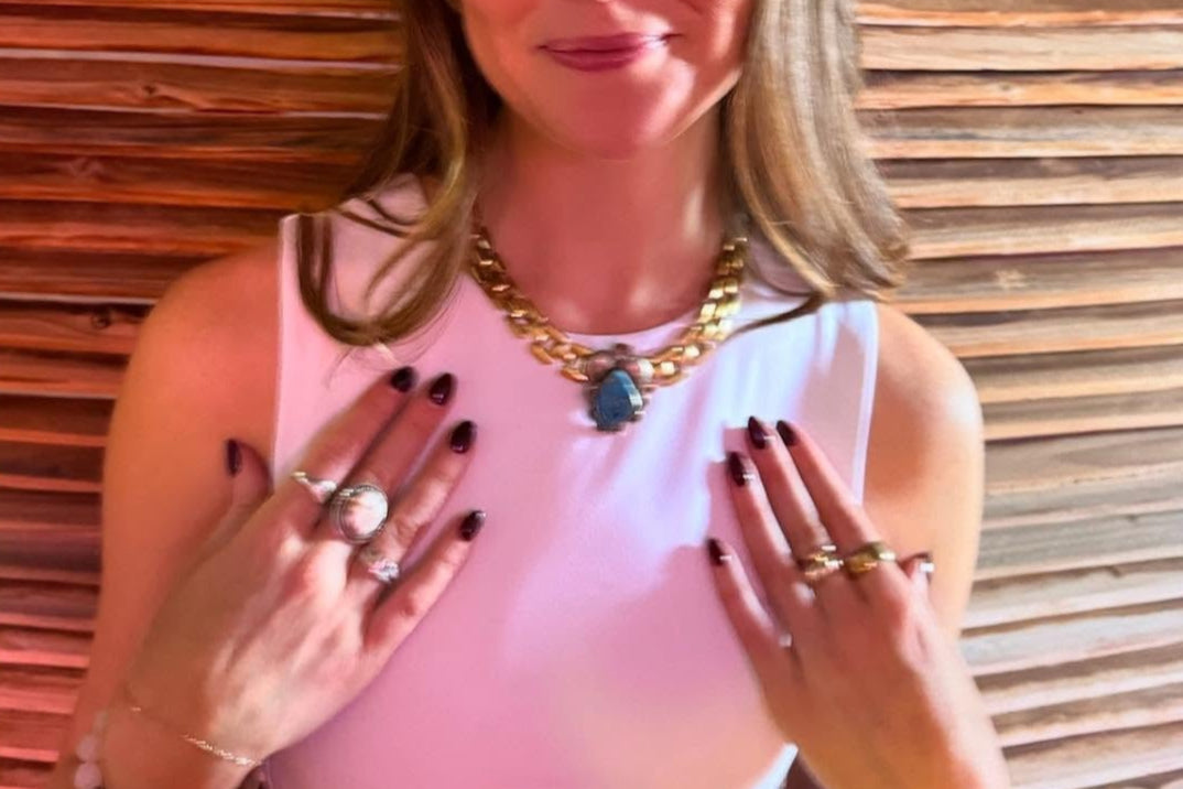 Woman posing with jewelry in front of a wooden panel background